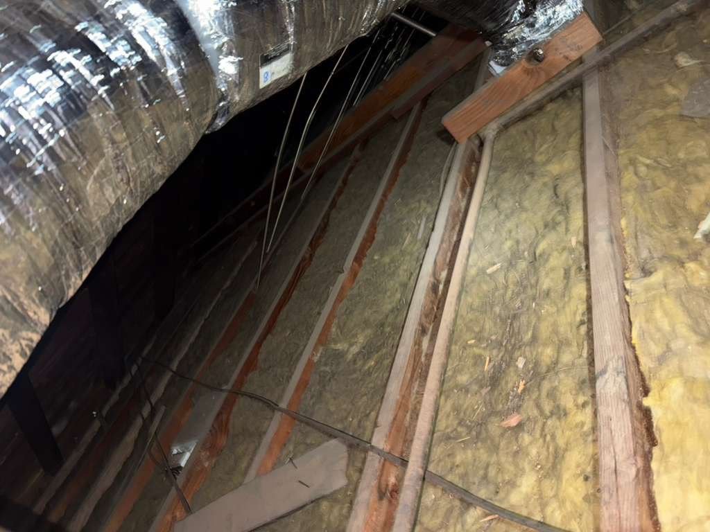 Thin old insulation between attic joists in Anaheim before work