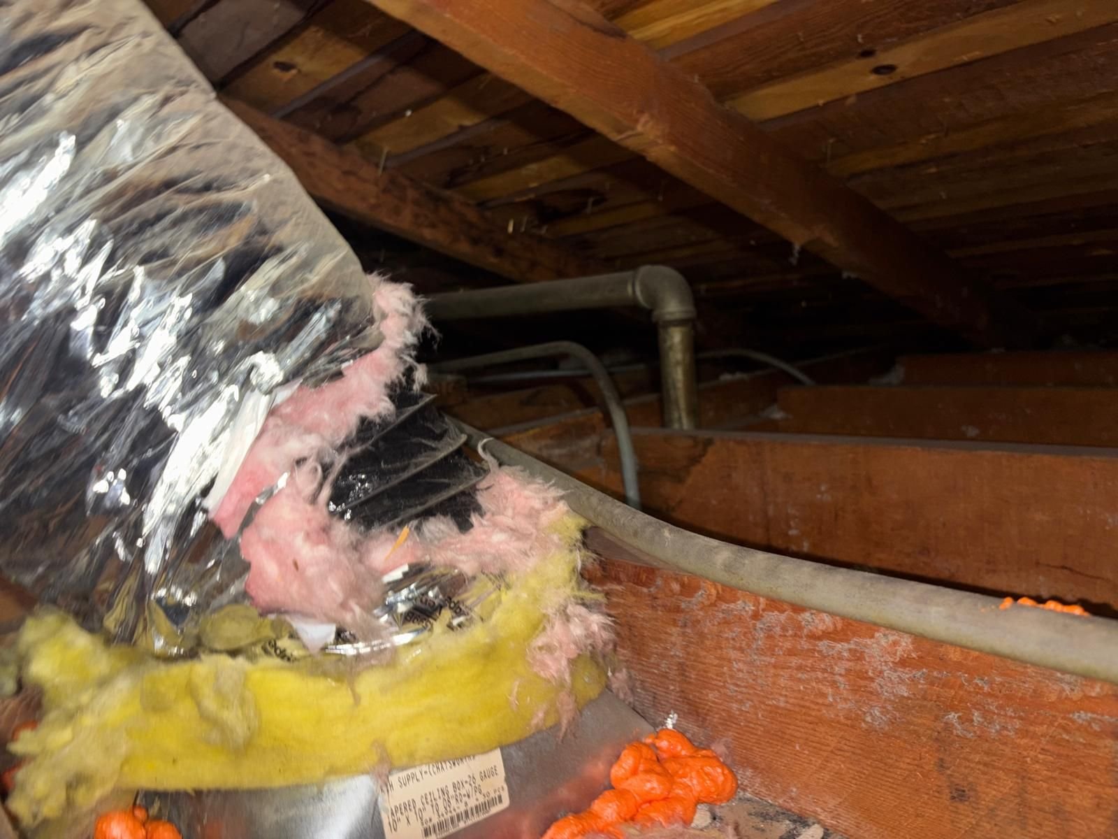 Old air duct with torn outer wrap in a Burbank attic before work
