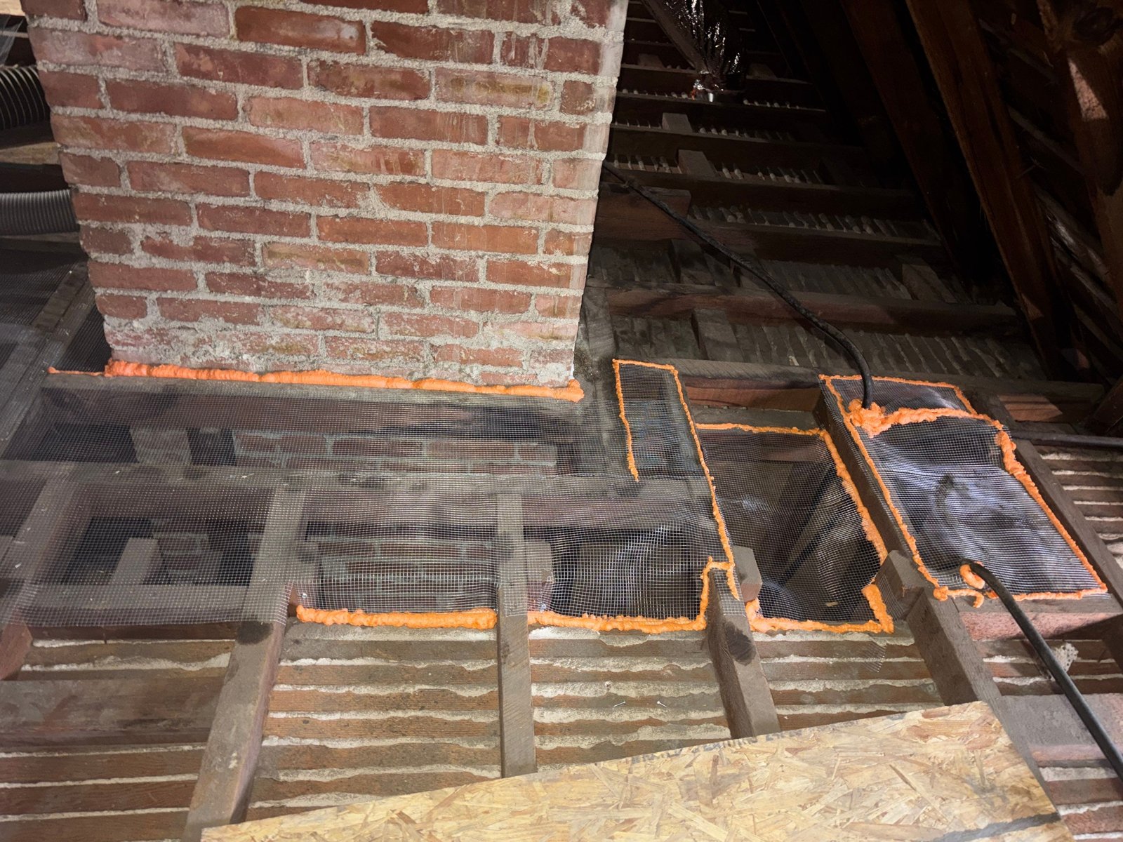 Foam and wire mesh sealing around a chimney in a Glendale attic