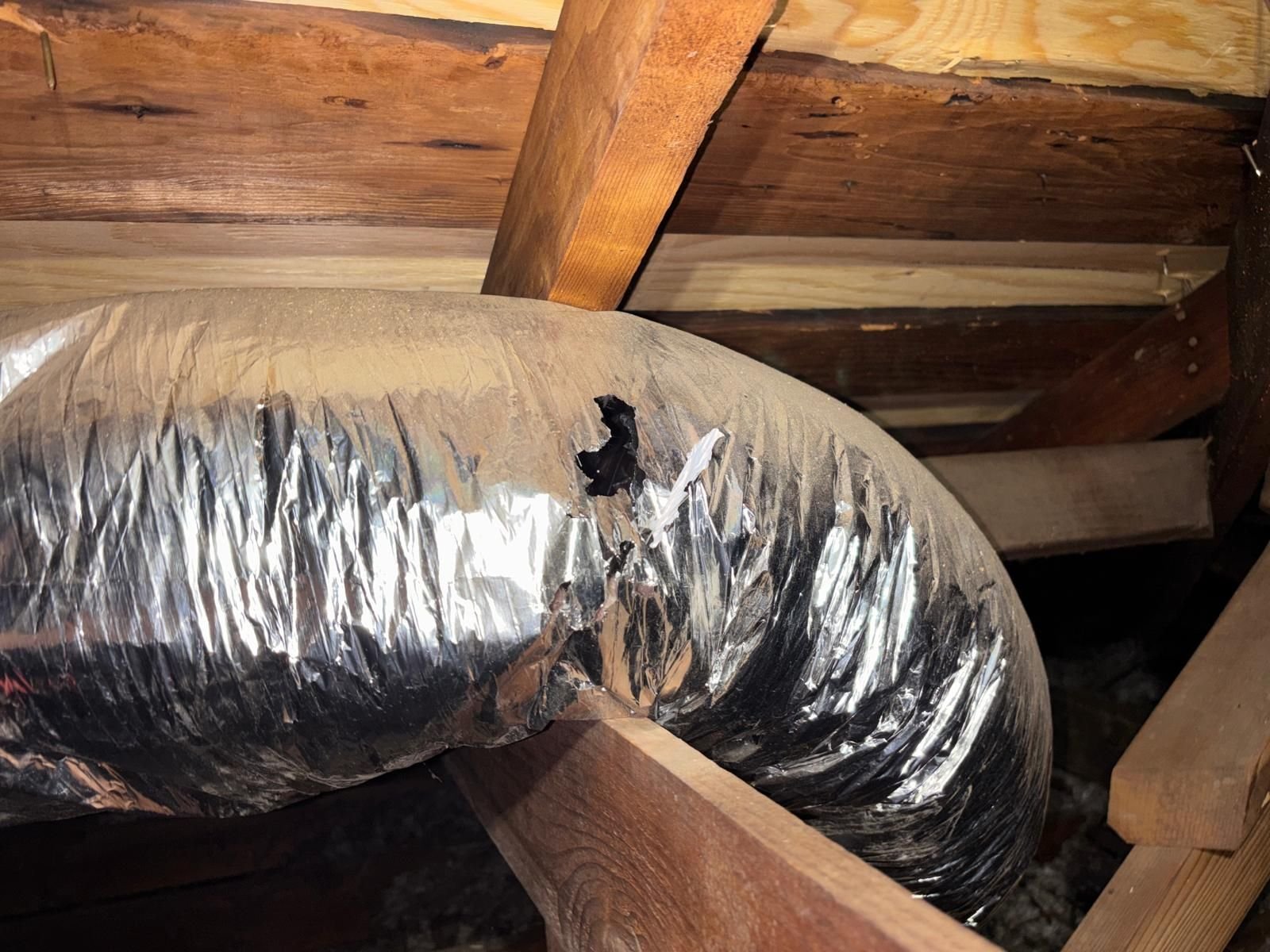 Old air duct with a torn jacket in a Long Beach attic before work