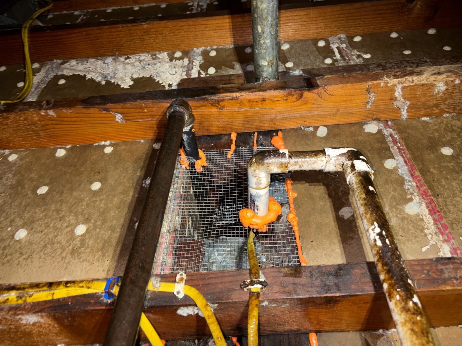 Wire mesh and foam sealed around pipes in a Long Beach attic