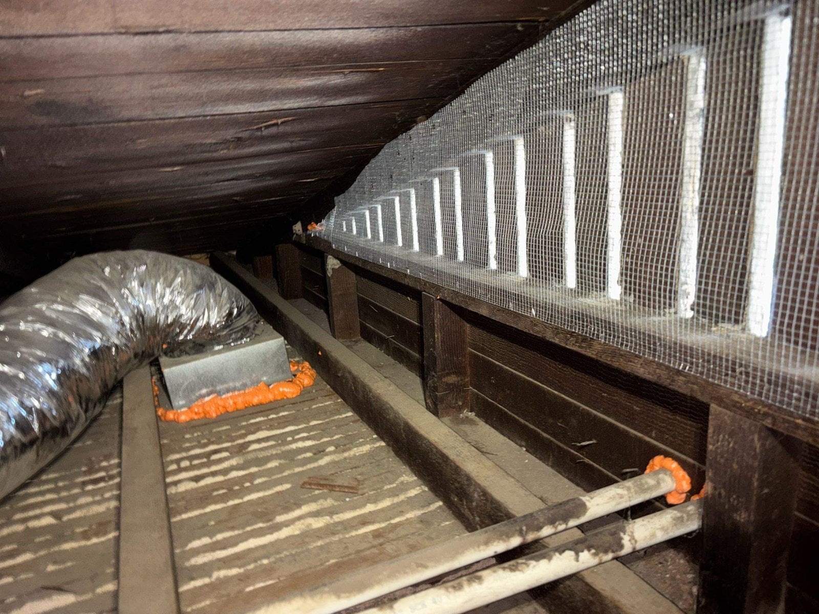 Wire-meshed attic vents and a new flexible duct in a Long Beach attic