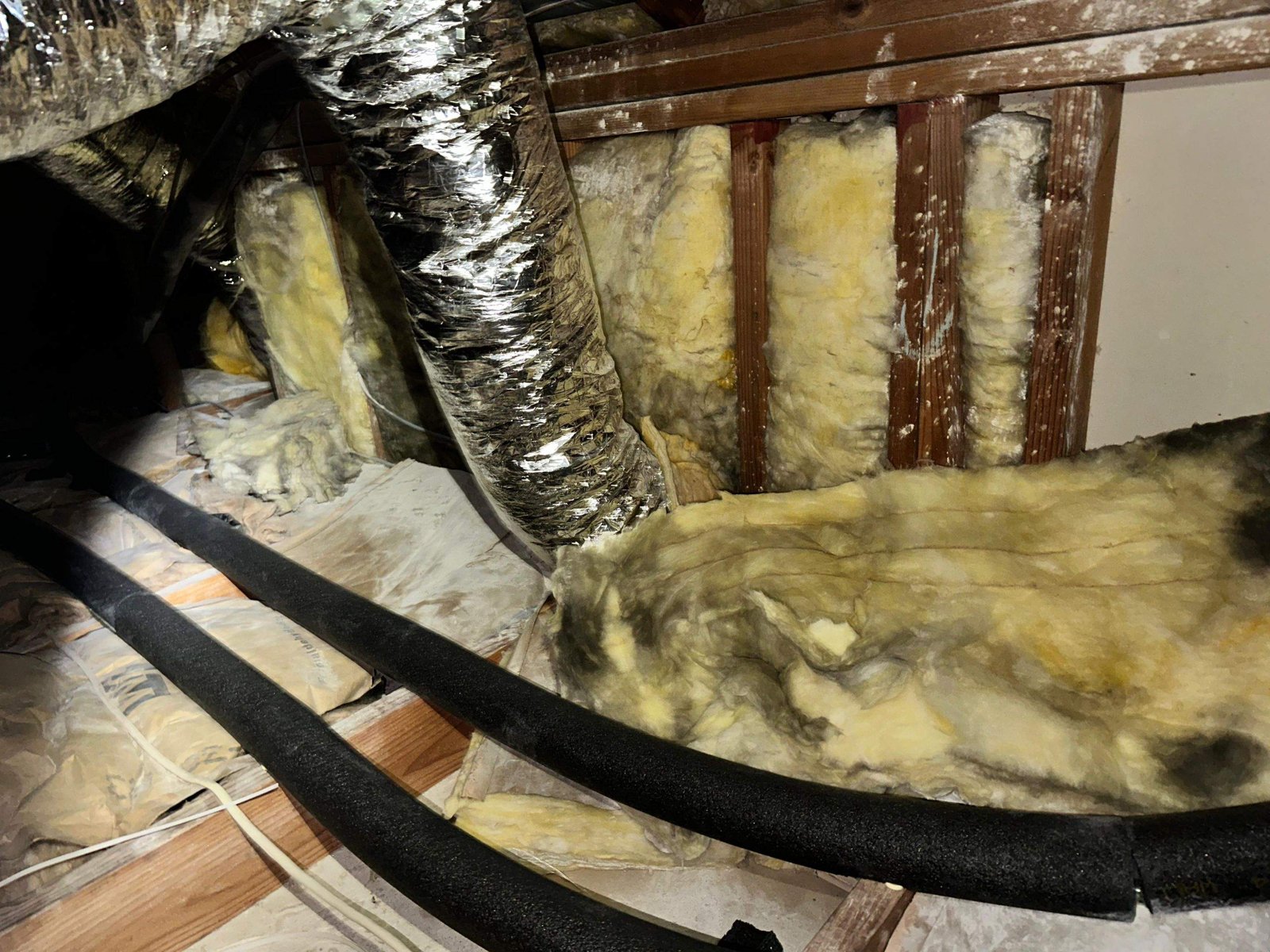 Stained old insulation batts in a Long Beach attic before work