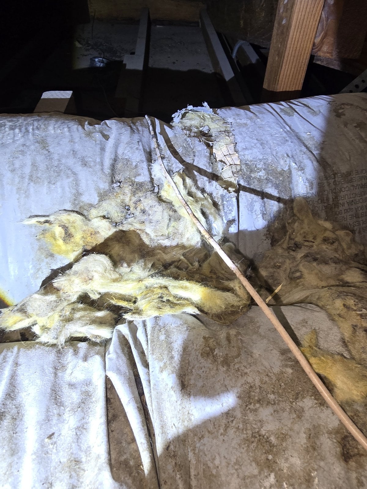 Old duct with torn wrap and old insulation in a Los Angeles attic before work