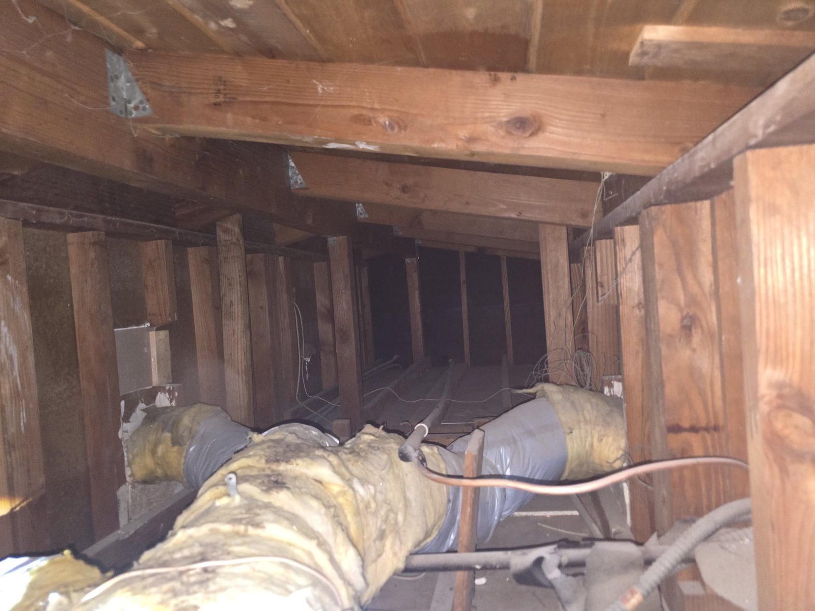 Old insulation around a duct run in a Los Angeles attic before work