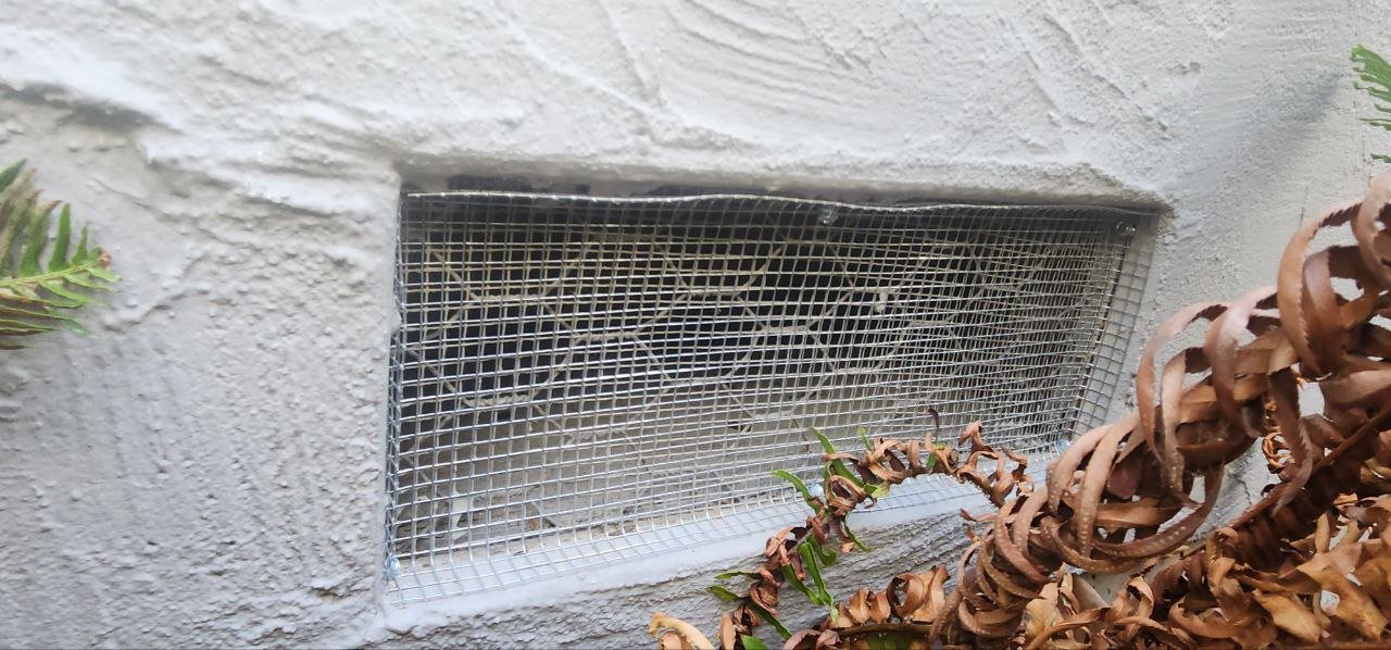 Foundation vent screened with wire mesh on a Mountain View home
