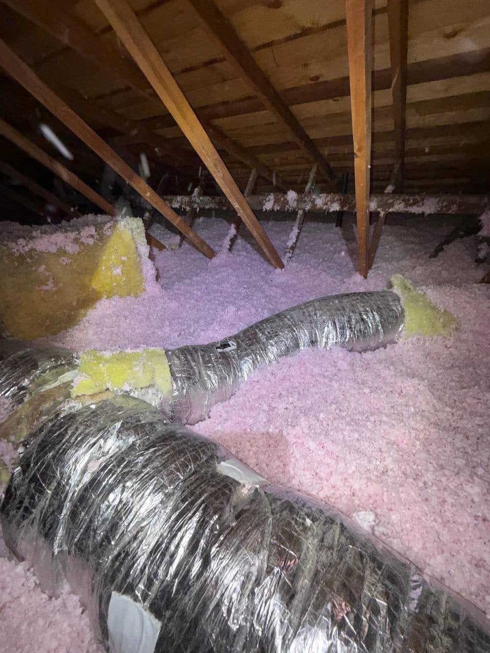 New blown-in insulation around flexible air ducts in a San Ramon attic