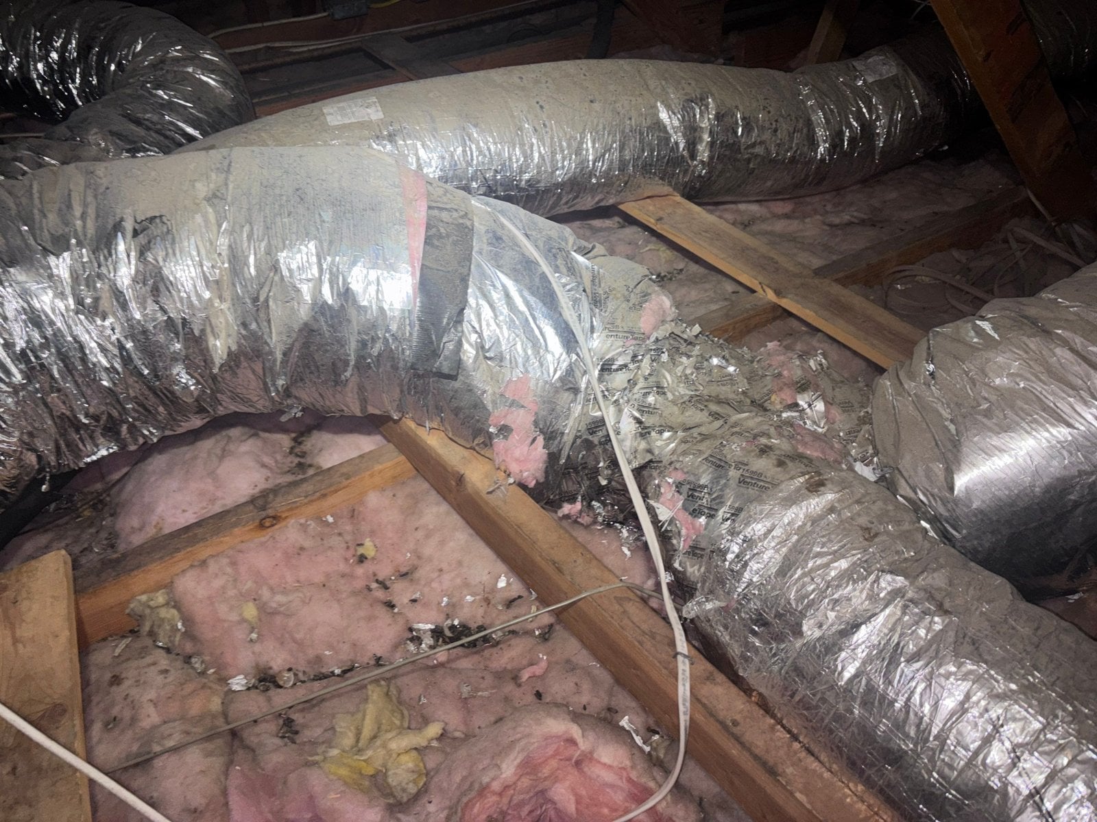 Old ducts over dirty insulation in a Santa Clarita attic before work