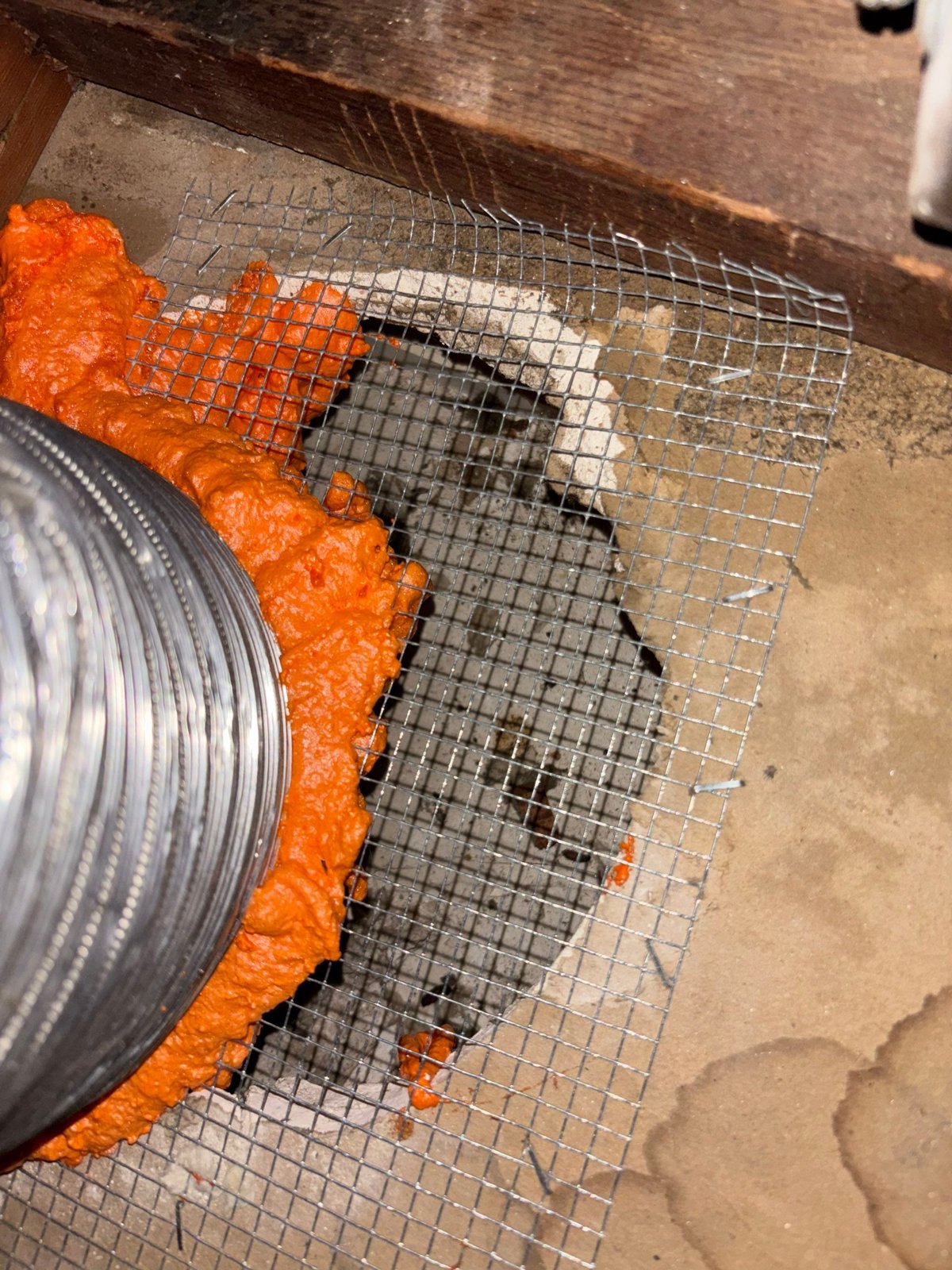 Wire mesh and foam sealing around a duct opening in a Upland attic