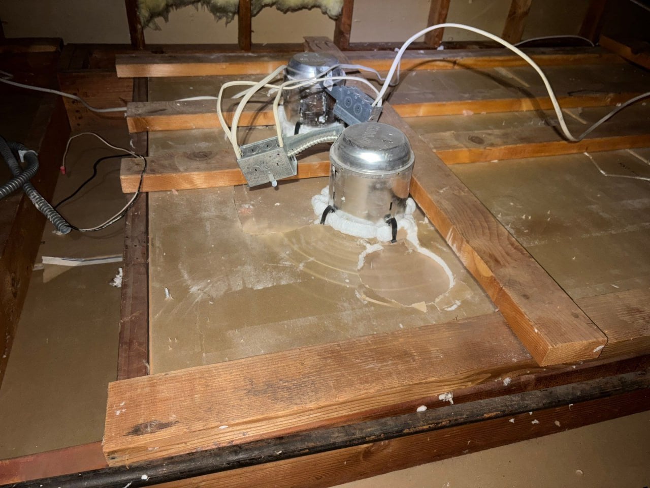 Foam sealing around a light fixture on a cleaned attic deck in Westlake Village